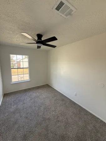 an empty room with windows and ceiling fan