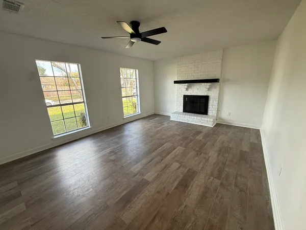 an empty room with windows and fireplace