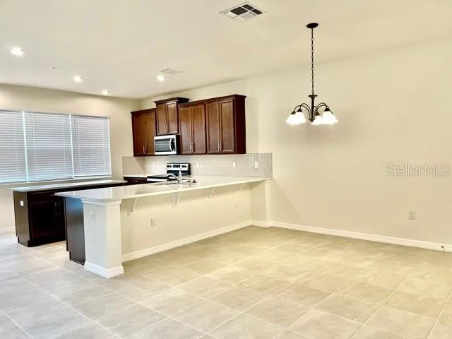 a kitchen with kitchen island granite countertop stainless steel appliances a sink a counter top space cabinets and a counter top