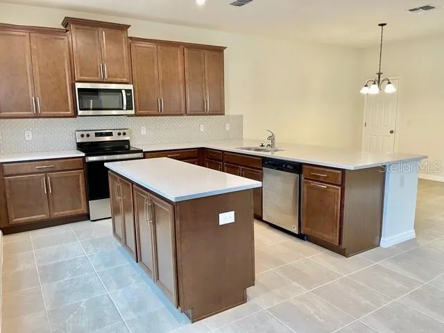 a kitchen with stainless steel appliances granite countertop a sink a stove and a microwave