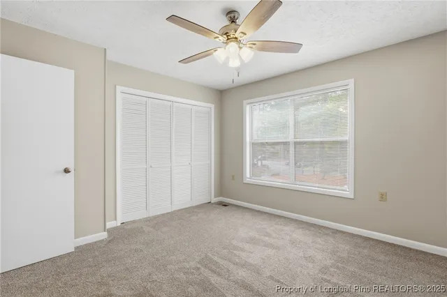 an empty room with chandelier fan and windows