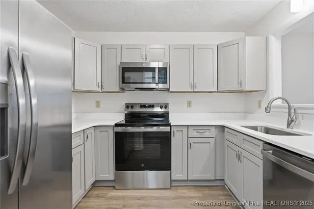 a kitchen with cabinets stainless steel appliances and sink