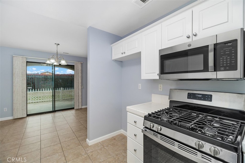 1078 Merrill Circle Hemet, CA 92545 - Photo 13 of 33 a kitchen with stainless steel appliances a stove a microwave and a white cabinets