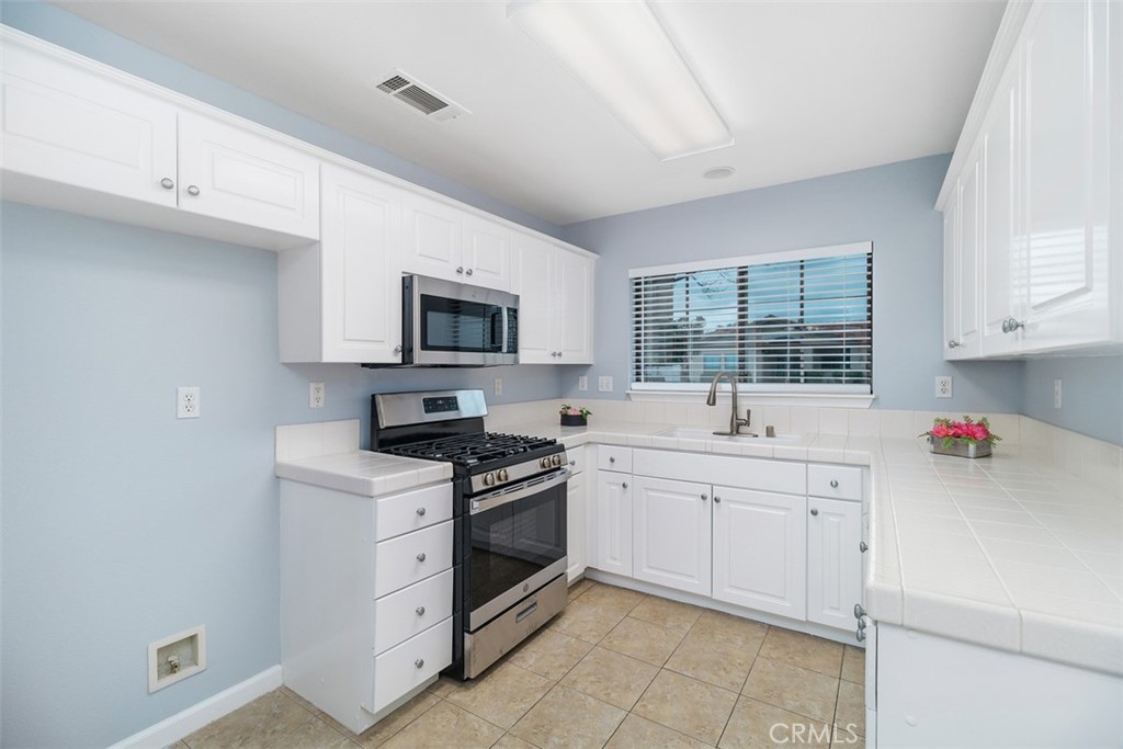 1078 Merrill Circle Hemet, CA 92545 - Photo 10 of 33 a kitchen with white cabinets a sink dishwasher and a stove with wooden floor