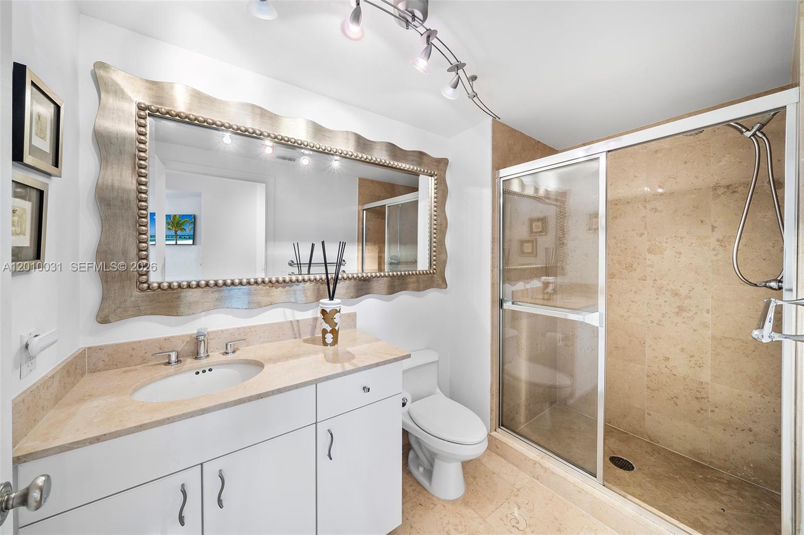 4779 Collins Avenue, Unit 2404 Miami Beach, FL 33140 - Photo 15 of 26 a bathroom with a shower sink vanity mirror and toilet