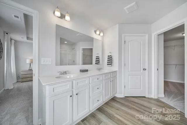 a spacious bathroom with a double vanity sink a mirror and a shower
