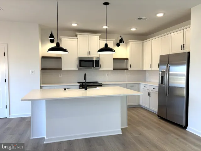 a large kitchen with kitchen island a stove a sink a center island and wooden floor