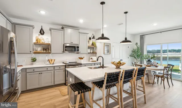a kitchen with stainless steel appliances a dining table chairs sink and white cabinets