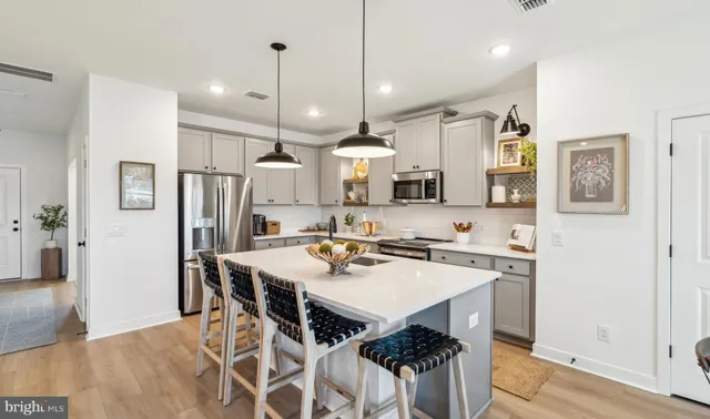 a kitchen with stainless steel appliances a stove a table a sink refrigerator and cabinets