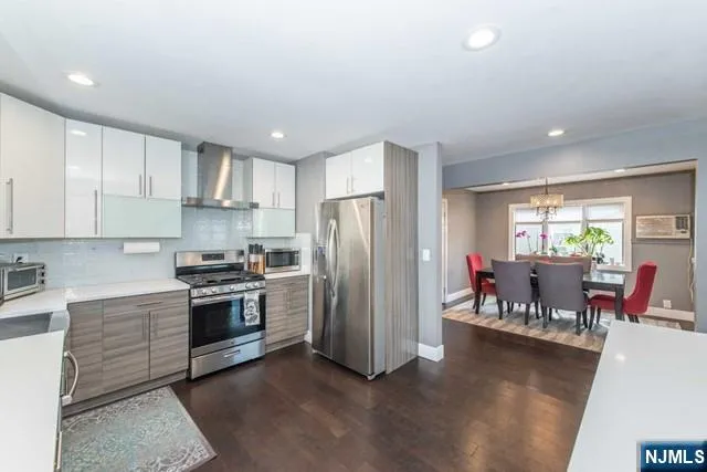 a kitchen with stainless steel appliances granite countertop a refrigerator stove top oven a sink dishwasher a dining table and chairs with wooden floor