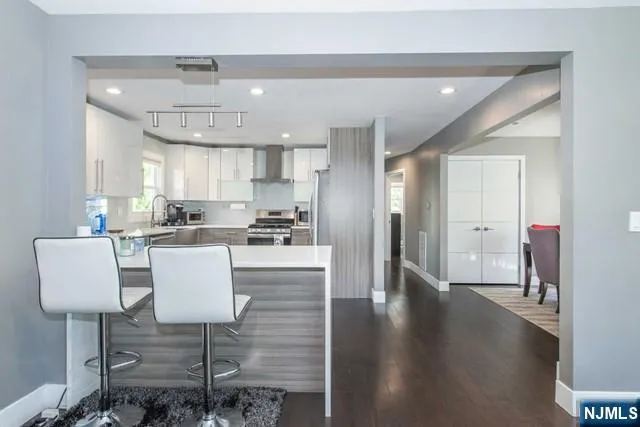 a living room with couches chairs and kitchen view with wooden floor
