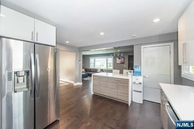 a view of kitchen with stainless steel appliances refrigerator stove and wooden floor