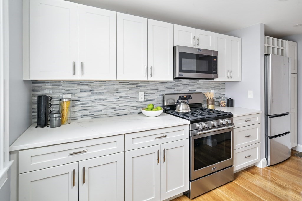 4 Spring St Place Cambridge, MA 02141 - Photo 4 of 12 a kitchen with stainless steel appliances granite countertop a sink a stove and a microwave