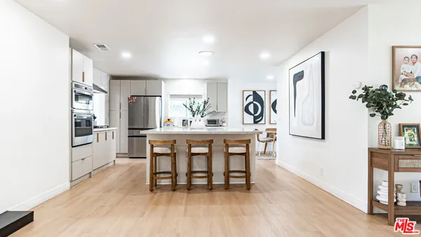 a kitchen with kitchen island a counter top space a sink stainless steel appliances and cabinets