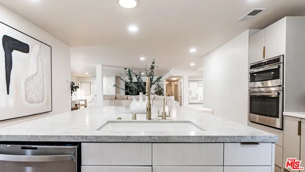 a kitchen with granite countertop kitchen island stainless steel appliances a sink and a dining table