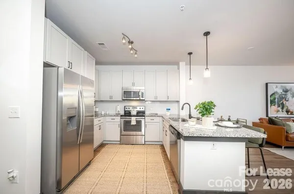 a kitchen with kitchen island granite countertop stainless steel appliances a sink refrigerator stove microwave and cabinets