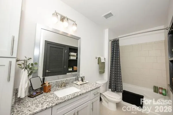 a bathroom with a granite countertop sink toilet and shower