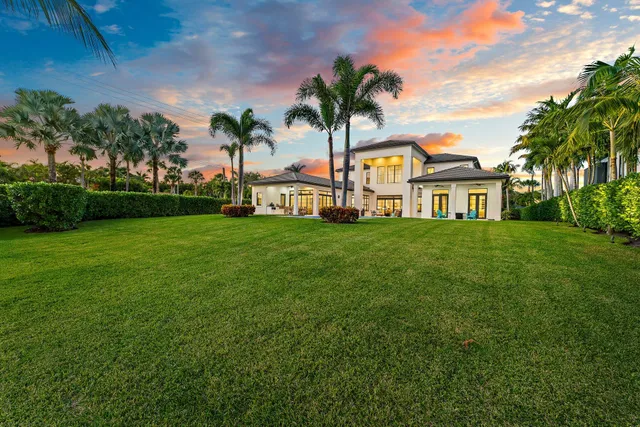 a view of a house with a big yard and palm trees