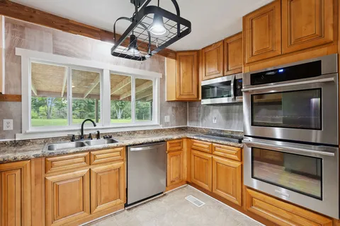 a kitchen with stainless steel appliances granite countertop a sink a stove and microwave