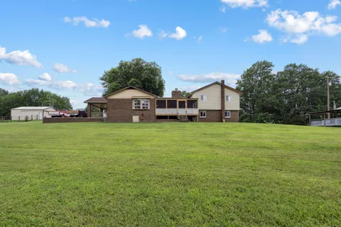 a view of a house with a big yard and large trees