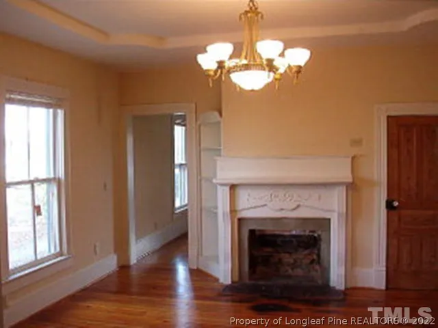 a view of a livingroom with a fireplace a chandelier and wooden floor