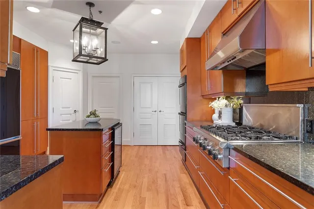 a kitchen with stainless steel appliances granite countertop a stove and a wooden floors