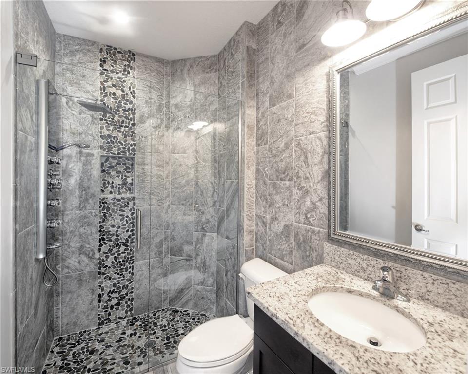 13693 Mandarin Circle Naples, FL 34109 - Photo 14 of 29 a bathroom with a granite countertop toilet a sink a mirror and shower