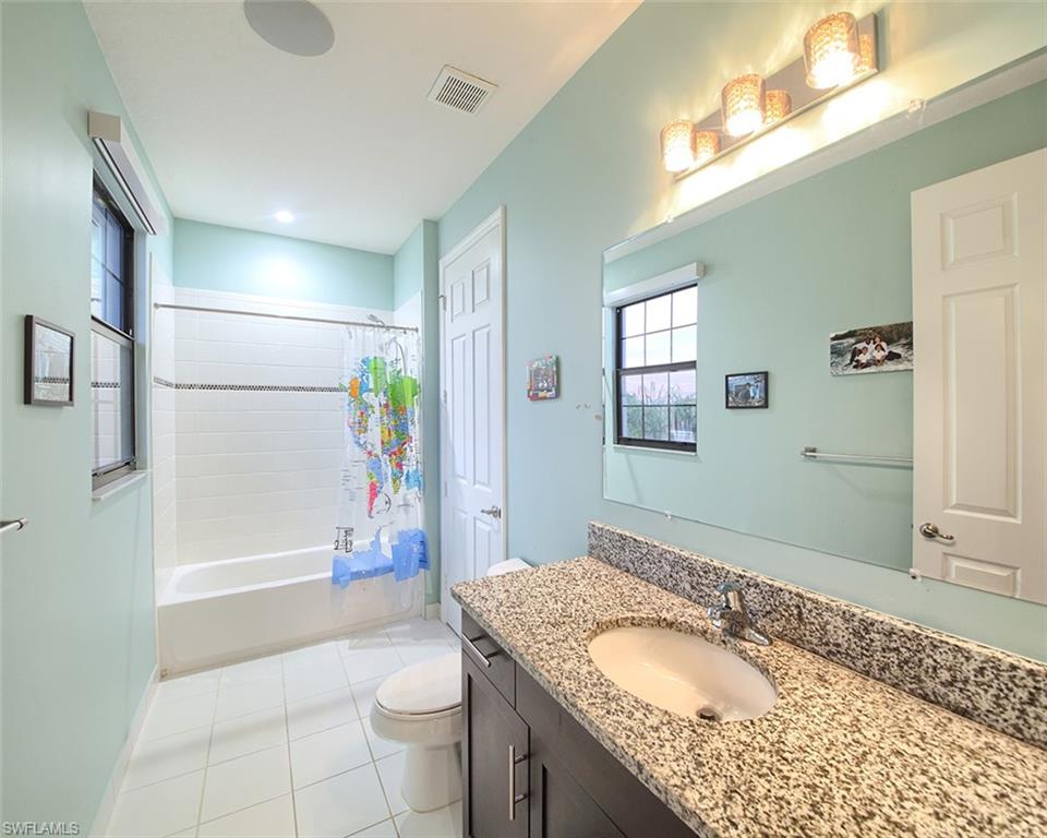 13693 Mandarin Circle Naples, FL 34109 - Photo 22 of 29 a bathroom with a granite countertop sink a toilet a mirror and shower
