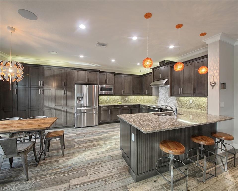 13693 Mandarin Circle Naples, FL 34109 - Photo 9 of 29 a kitchen with stainless steel appliances kitchen island granite countertop a table chairs sink and cabinets