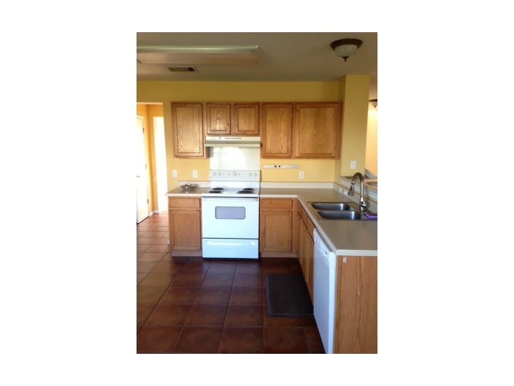 120 Rinehardt Street Hutto, TX 78634 - Photo 6 of 7 Kitchen featuring white appliances, light countertops, dark tile patterned floors, and brown cabinets