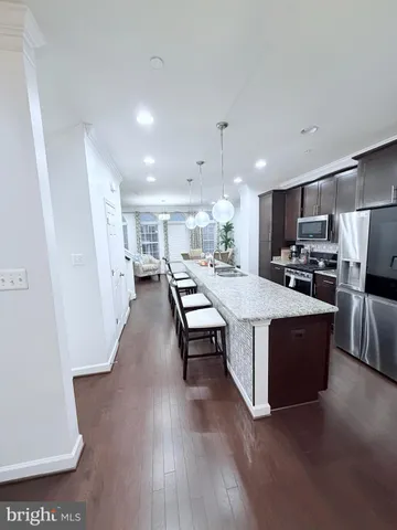 a living room with stainless steel appliances kitchen island granite countertop furniture a refrigerator a sink a stove a microwave a sink and white cabinets