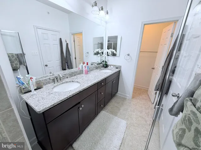a bathroom with a granite countertop sink a mirror a vanity and a shower