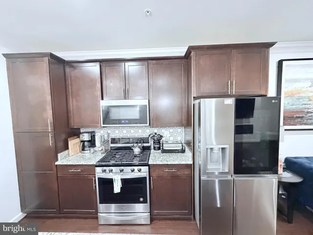 a kitchen with kitchen island granite countertop a refrigerator stove and sink