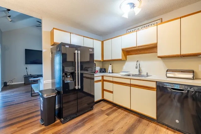 a kitchen with stainless steel appliances granite countertop a refrigerator a sink dishwasher a stove and white countertops with wooden floor