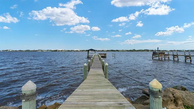 a view of white house with a large tree and wooden fence