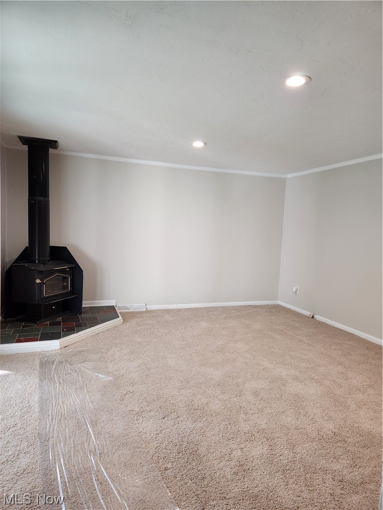 4660 West Farnhurst Road South Euclid, OH 44121 - Photo 7 of 17 Unfurnished living room with a wood stove, crown molding, and carpet flooring