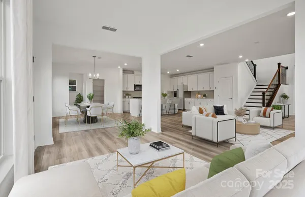 a living room with couches and kitchen view with wooden floor