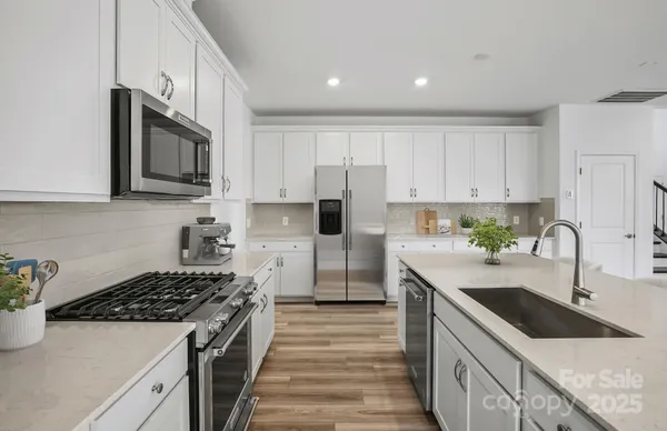 a kitchen with stainless steel appliances granite countertop a sink stove and refrigerator