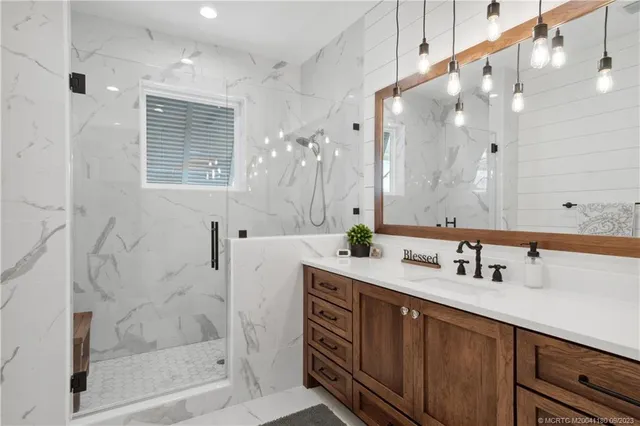 a bathroom with a granite countertop sink mirror and a shower