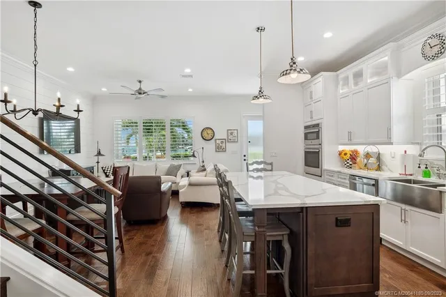 a large kitchen with sink a center island stainless steel appliances and living room view