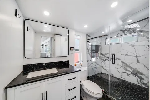 a bathroom with a granite countertop sink mirror vanity and toilet