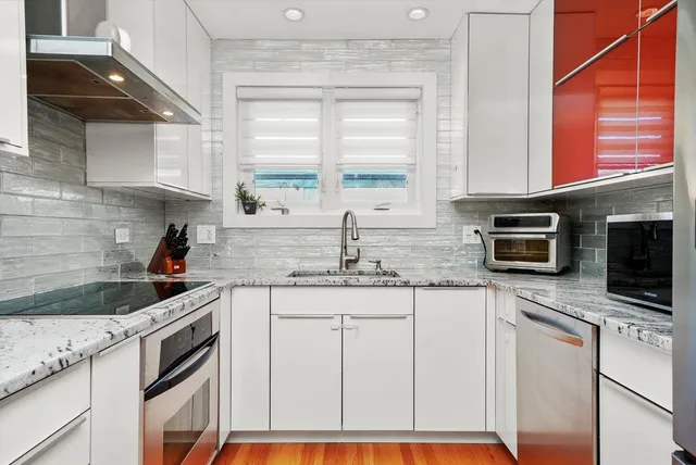 a kitchen with stainless steel appliances granite countertop a sink a stove a microwave and wooden cabinets