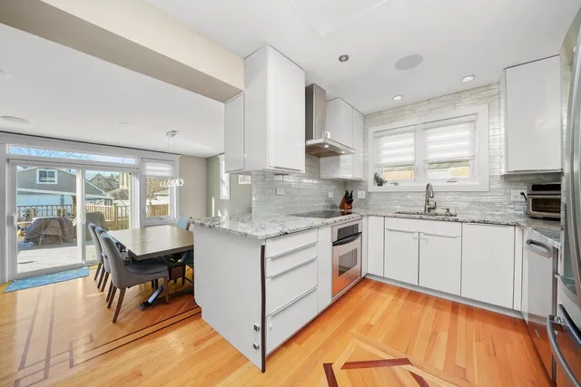a kitchen with a stove a sink and white cabinets with wooden floors