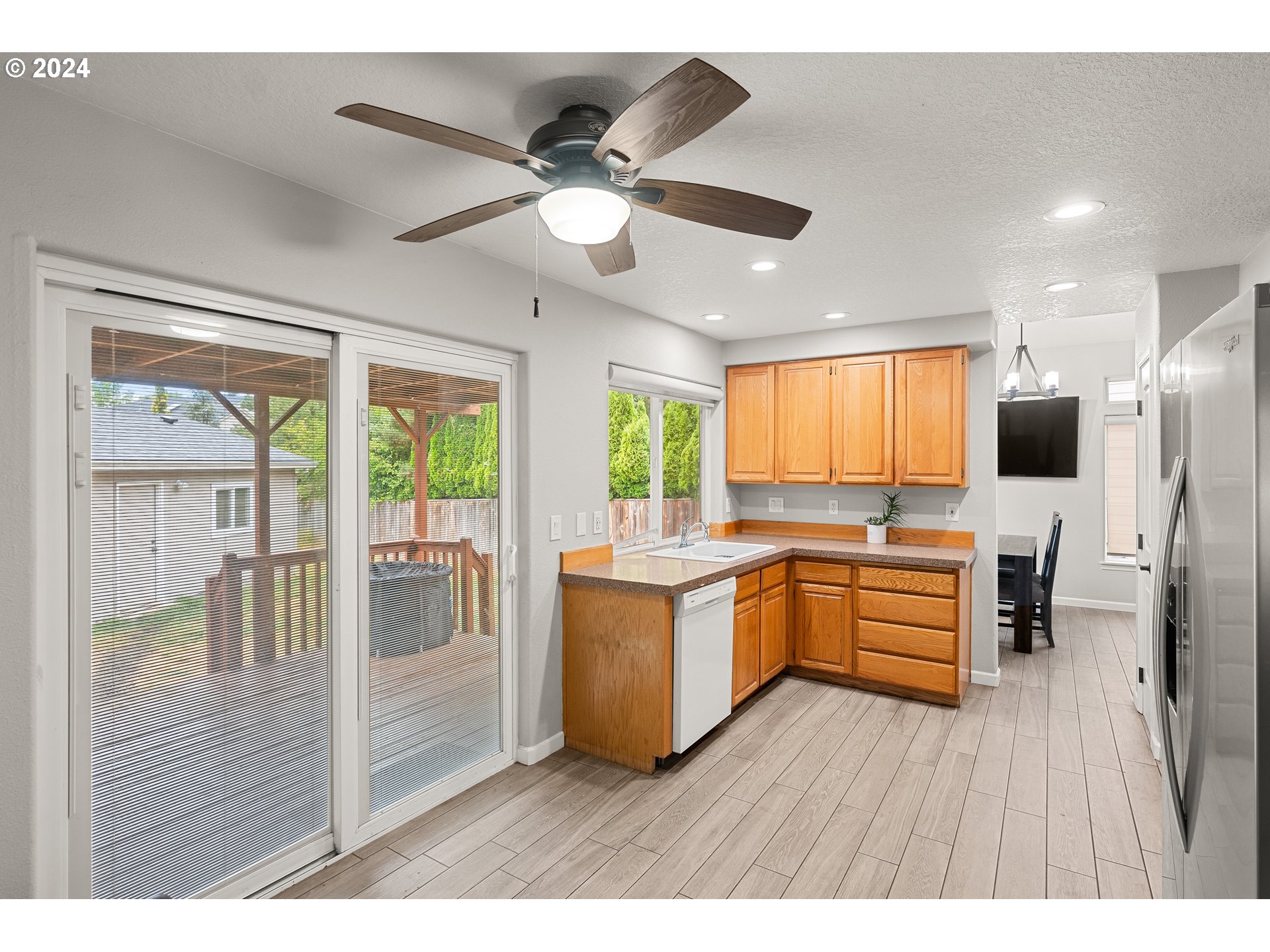 216 Southwest Sutherland Way Beaverton, OR 97006 - Photo 7 of 19 a kitchen with stainless steel appliances kitchen island granite countertop a stove a refrigerator a sink a dining table and chairs with wooden floor