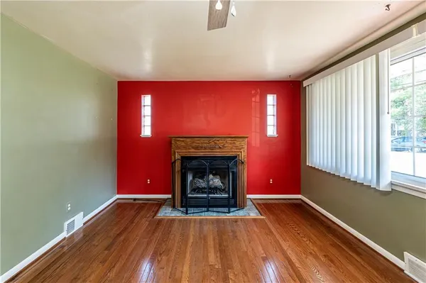 a view of an empty room with wooden floor fireplace and a window