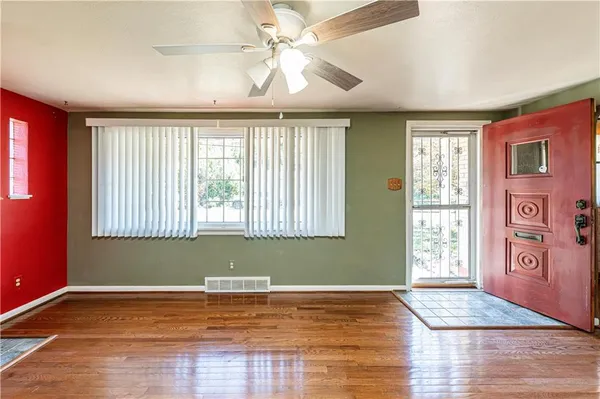 a view of an empty room with window and wooden floor