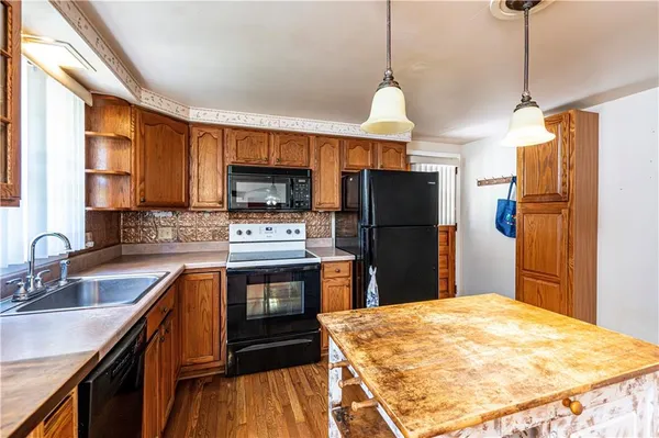 a kitchen with stainless steel appliances granite countertop a refrigerator a sink dishwasher a stove and a sink with wooden floor