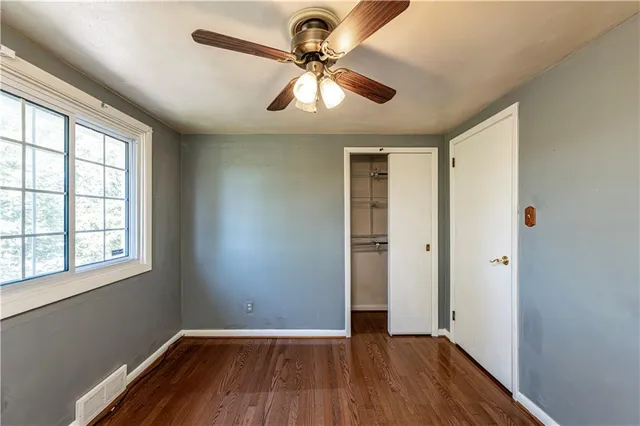 a view of empty room with wooden floor and fan