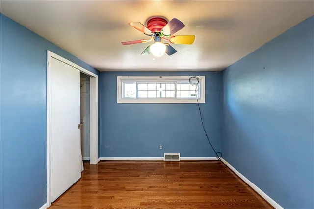 a view of an empty room with window and wooden floor