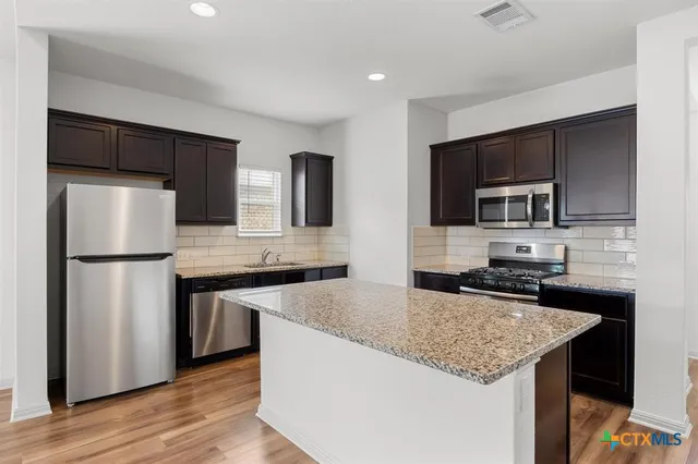 a kitchen with stainless steel appliances granite countertop a sink stove and refrigerator